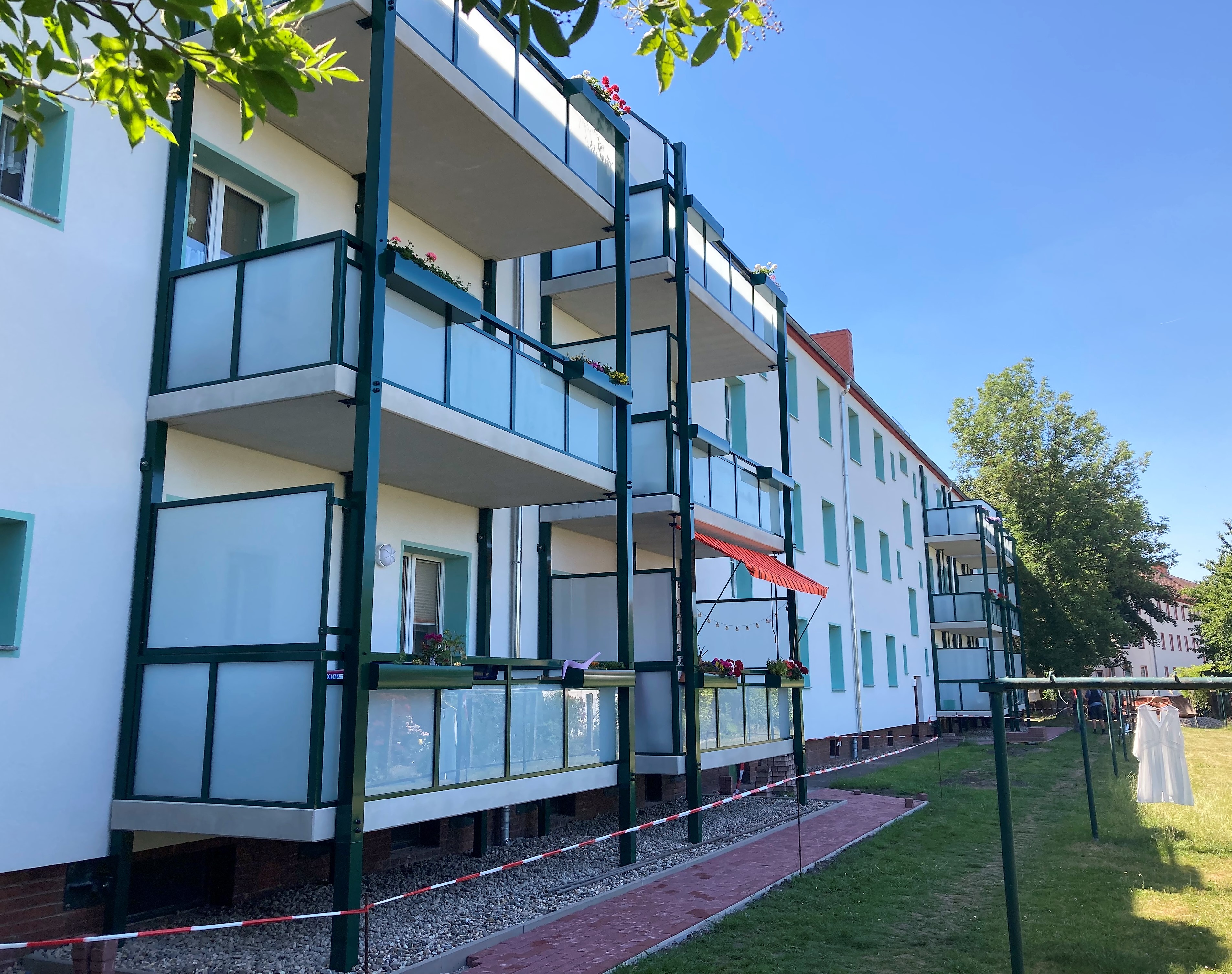 Modernisiertes Wohnhaus mit gelber Fassade und grünen Balkonen