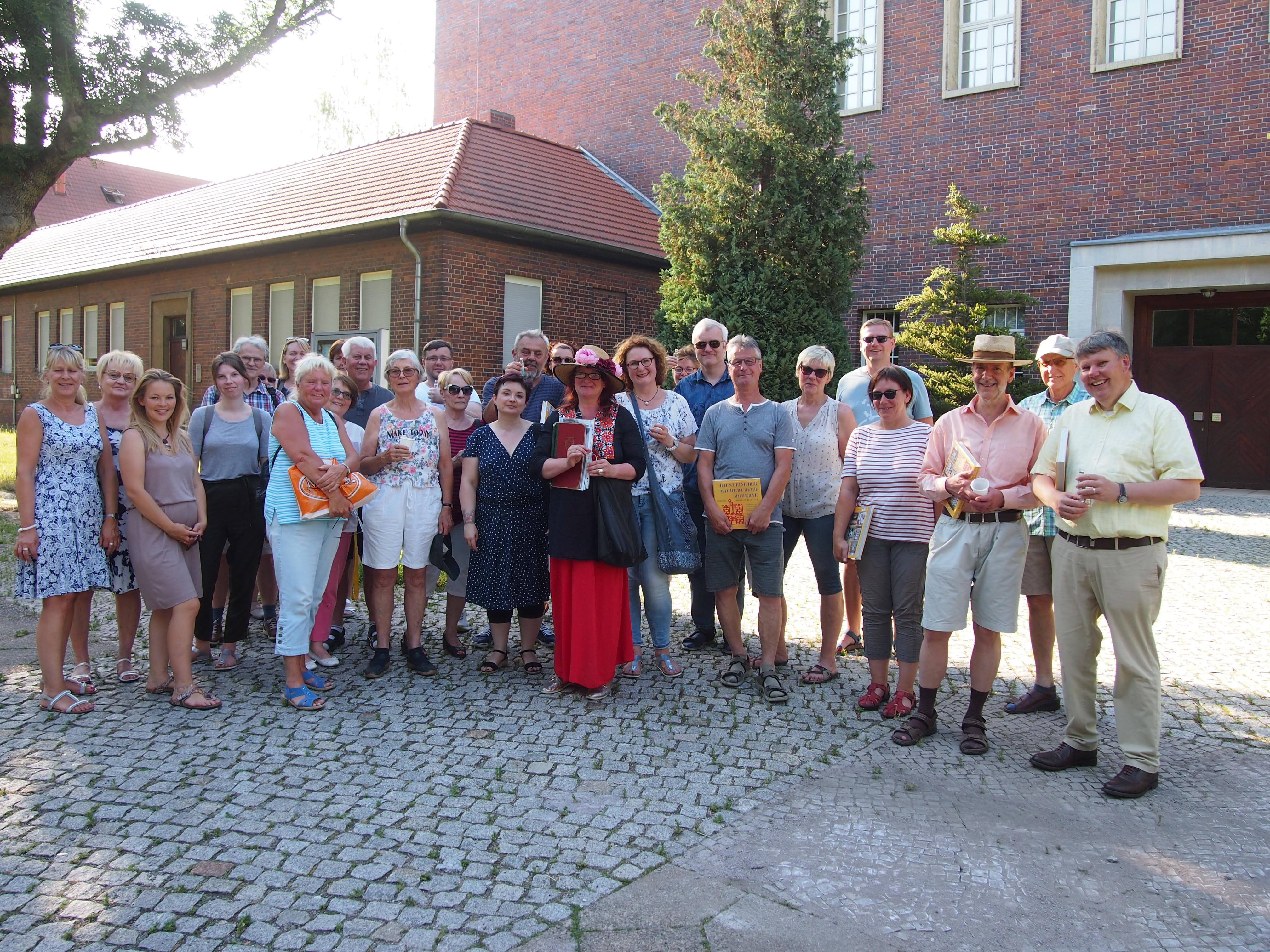 Gruppe von Menschen stehen vor alten Backsteingebäuden im Bauhaus-Stil