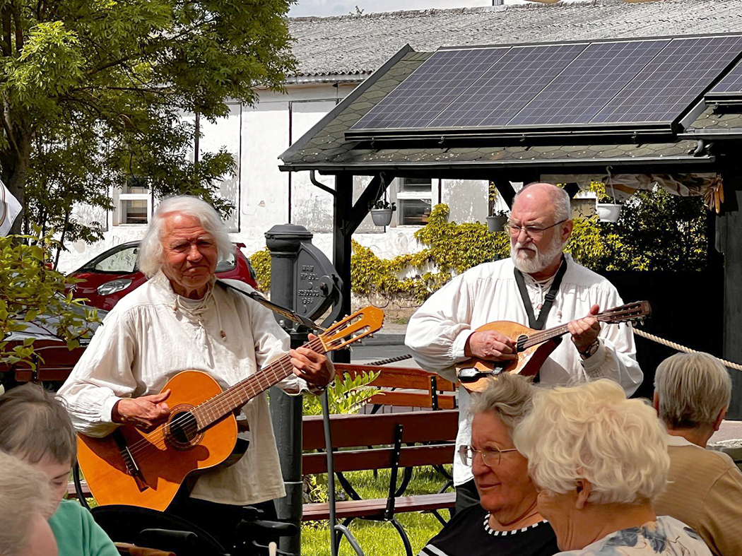 Zwei Musiker spielen vor Gästen im Außenbereich eines Restaurants.